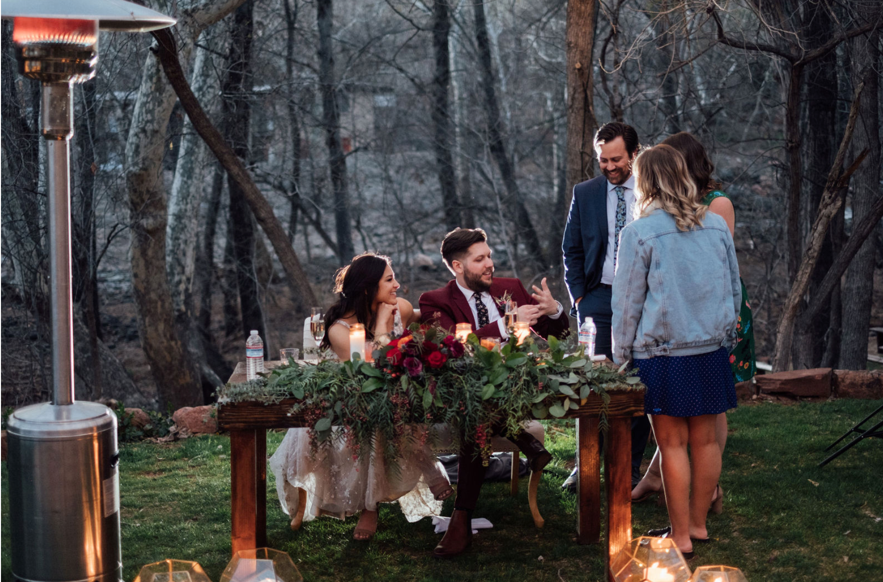 A bride and groom posing behind their sweetheart table flowers after sunset