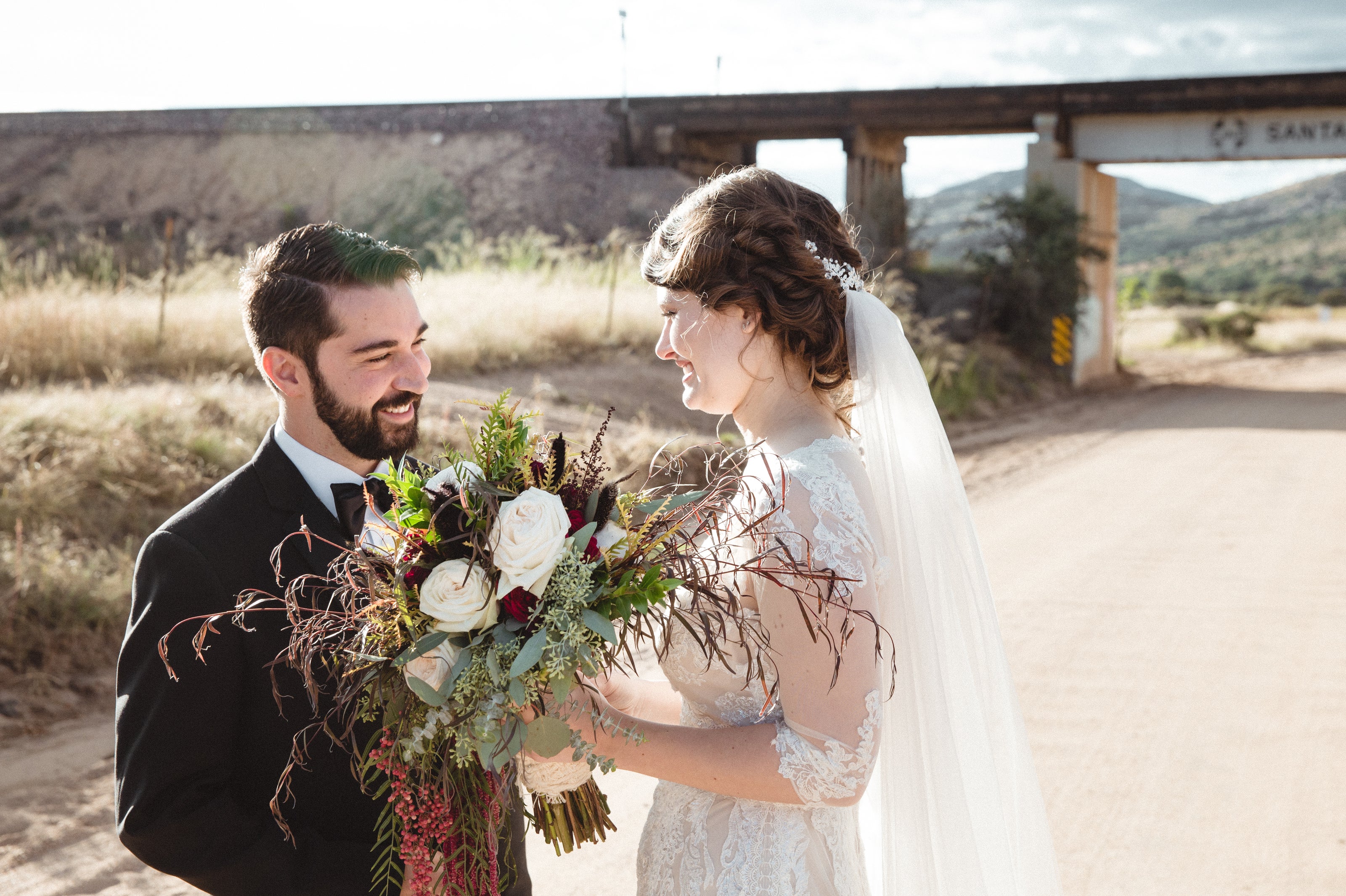 Bride and groom in Prescott Arizona, holding her bouquet containing fall colored flowers