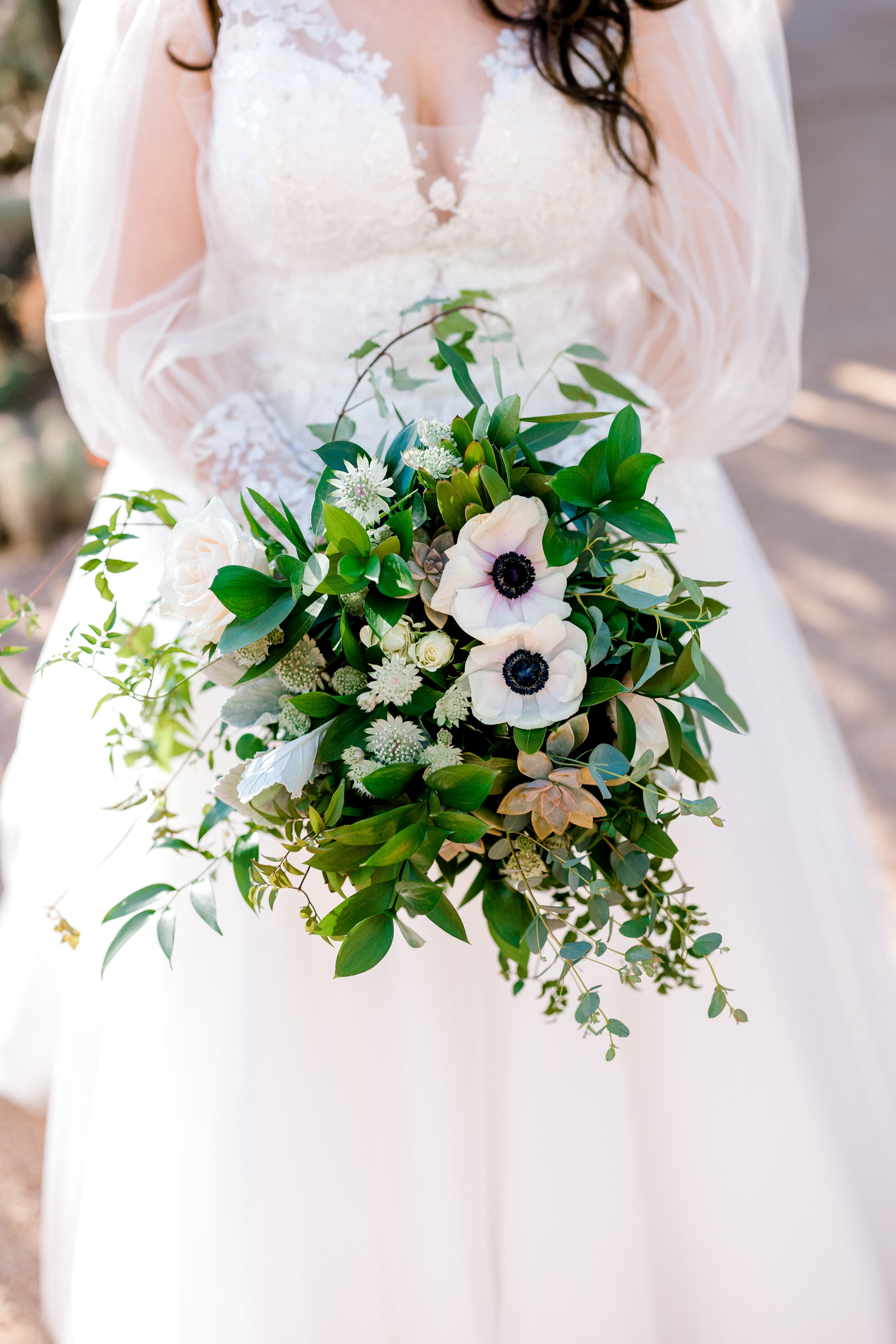 Bride holding bouquet of greenery and white flowers at a desert wedding