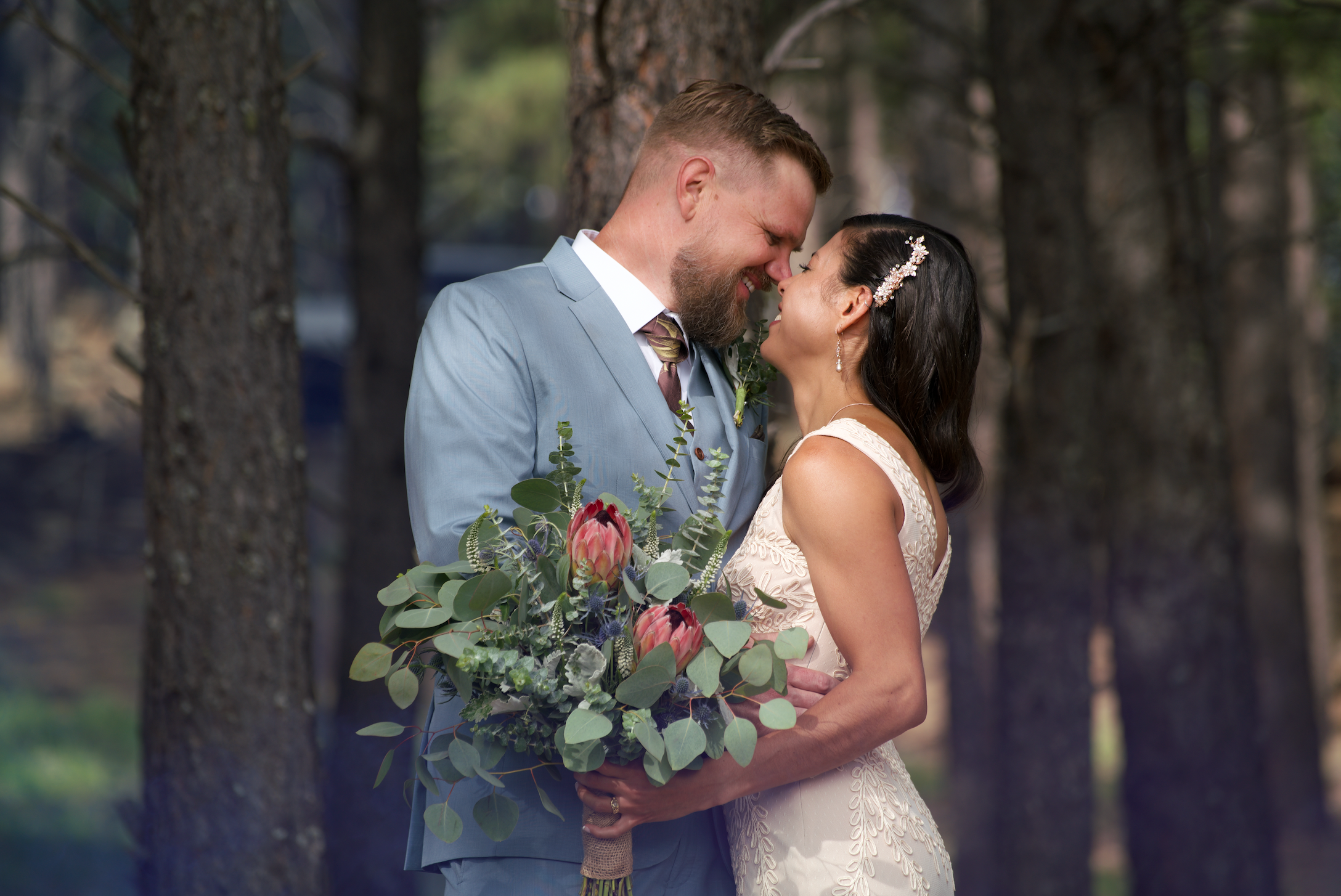 Smiling bride and groom holding a wedding bouquet containing eucalyptus and protea