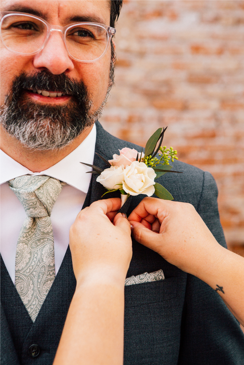 Boutonniere being pinned onto a grey suit at Tre Bella