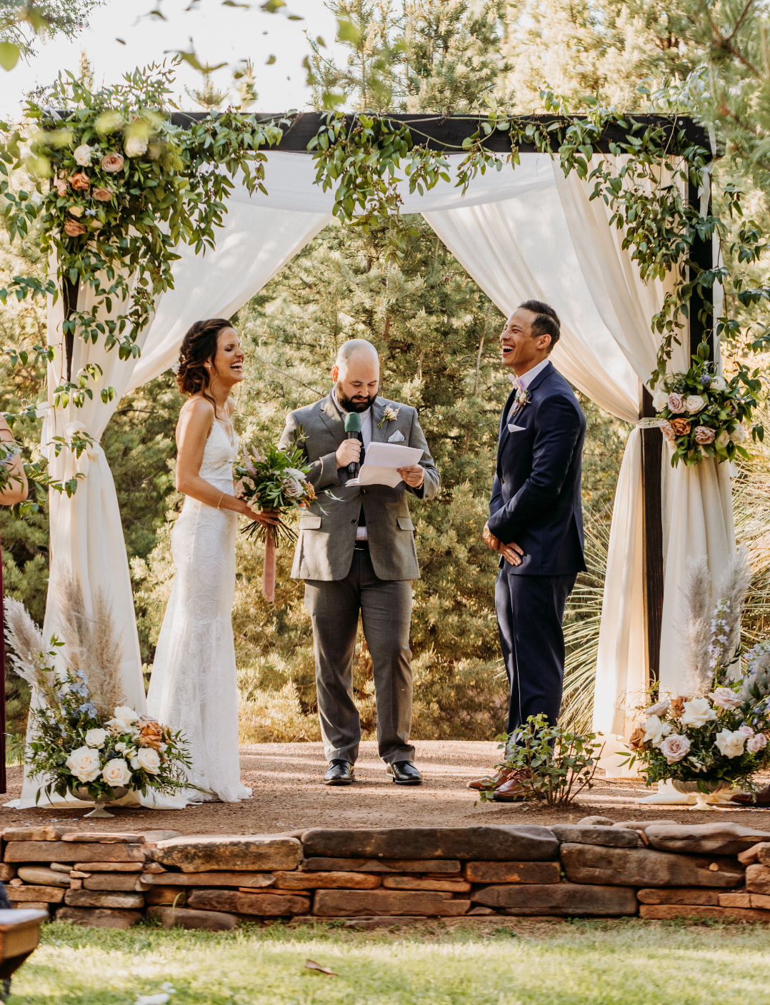 Bride and groom under a ceremony arch of smilax and flowers at their desert wedding