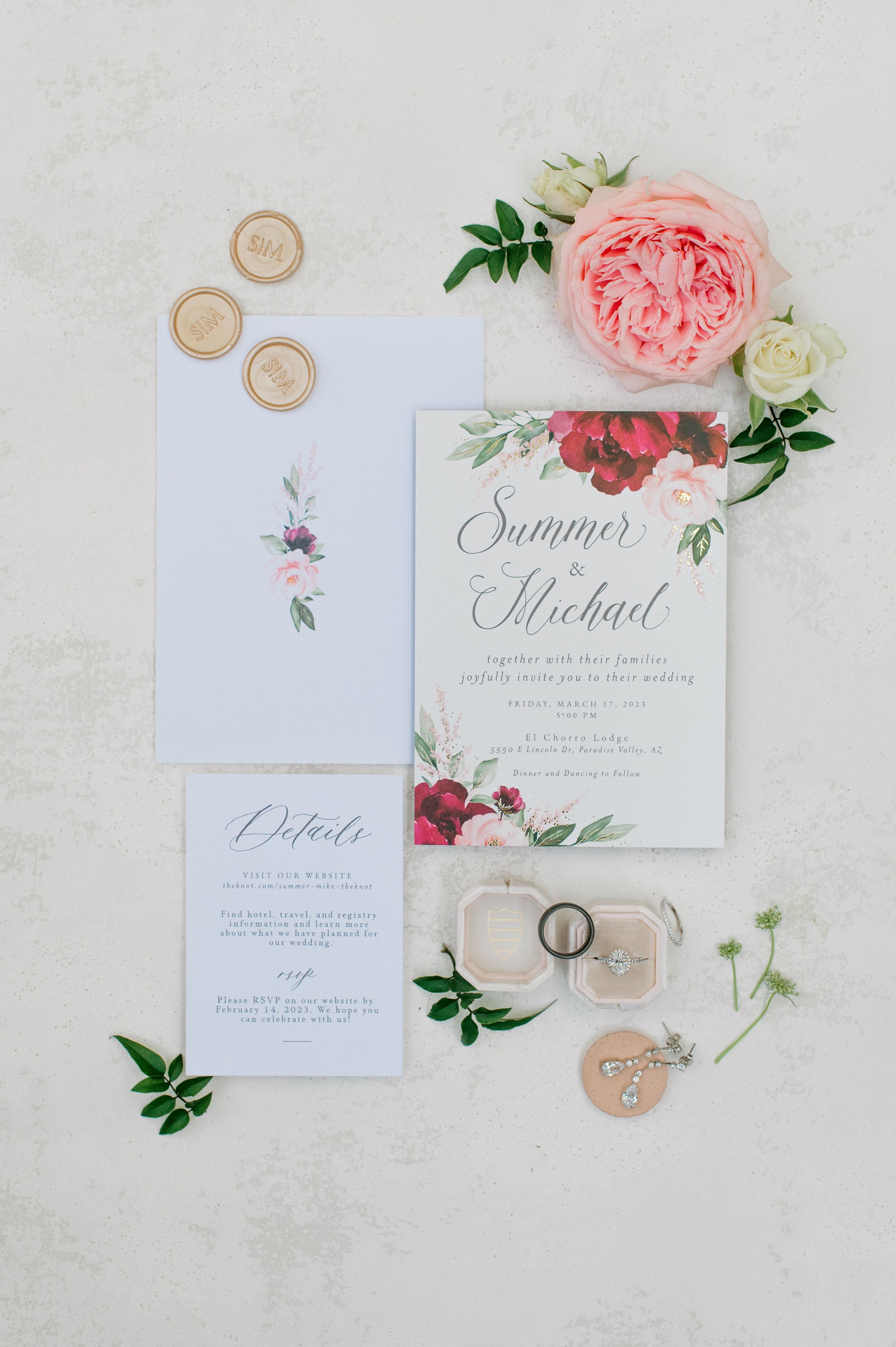 Pink garden roses next to wedding invitation flat lay
