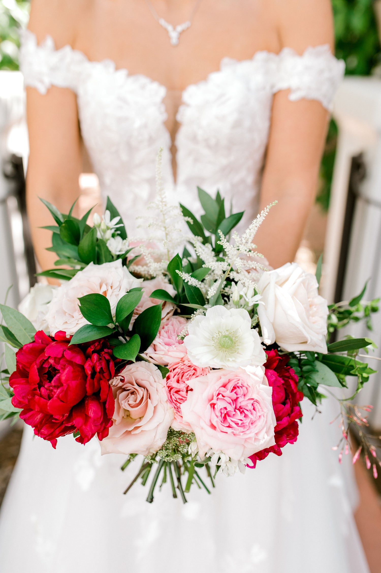 Close up image of bridal bouquet containing garden roses, peonies, anemone, and greenery